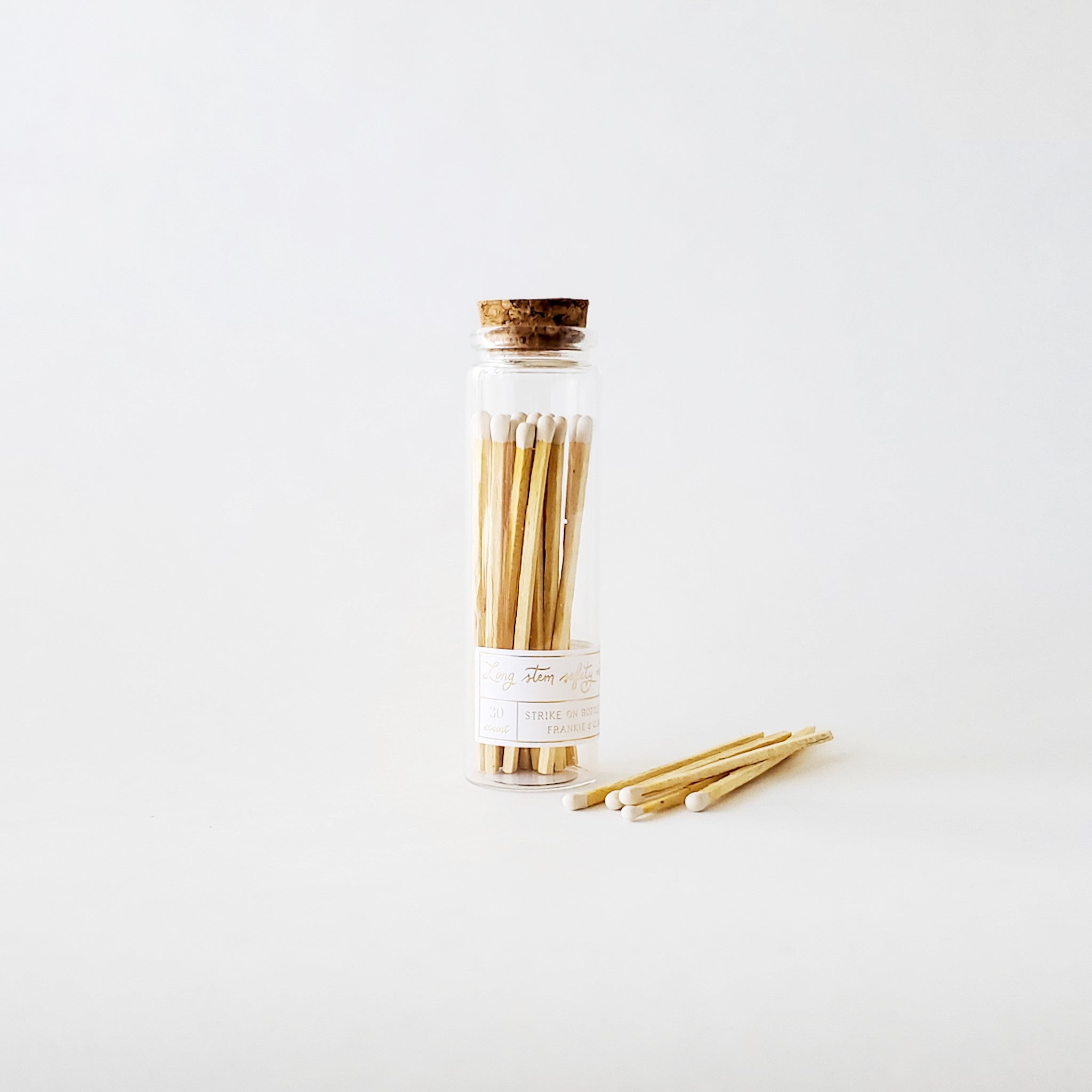 A corked jar of matches with a white label. The head's of the matches are white.