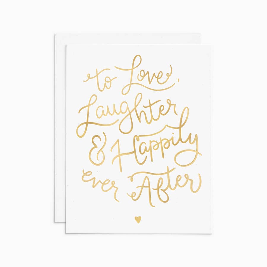 A white card with gold lettering which reads "to love, laughter, & happily ever after" in a playful script.