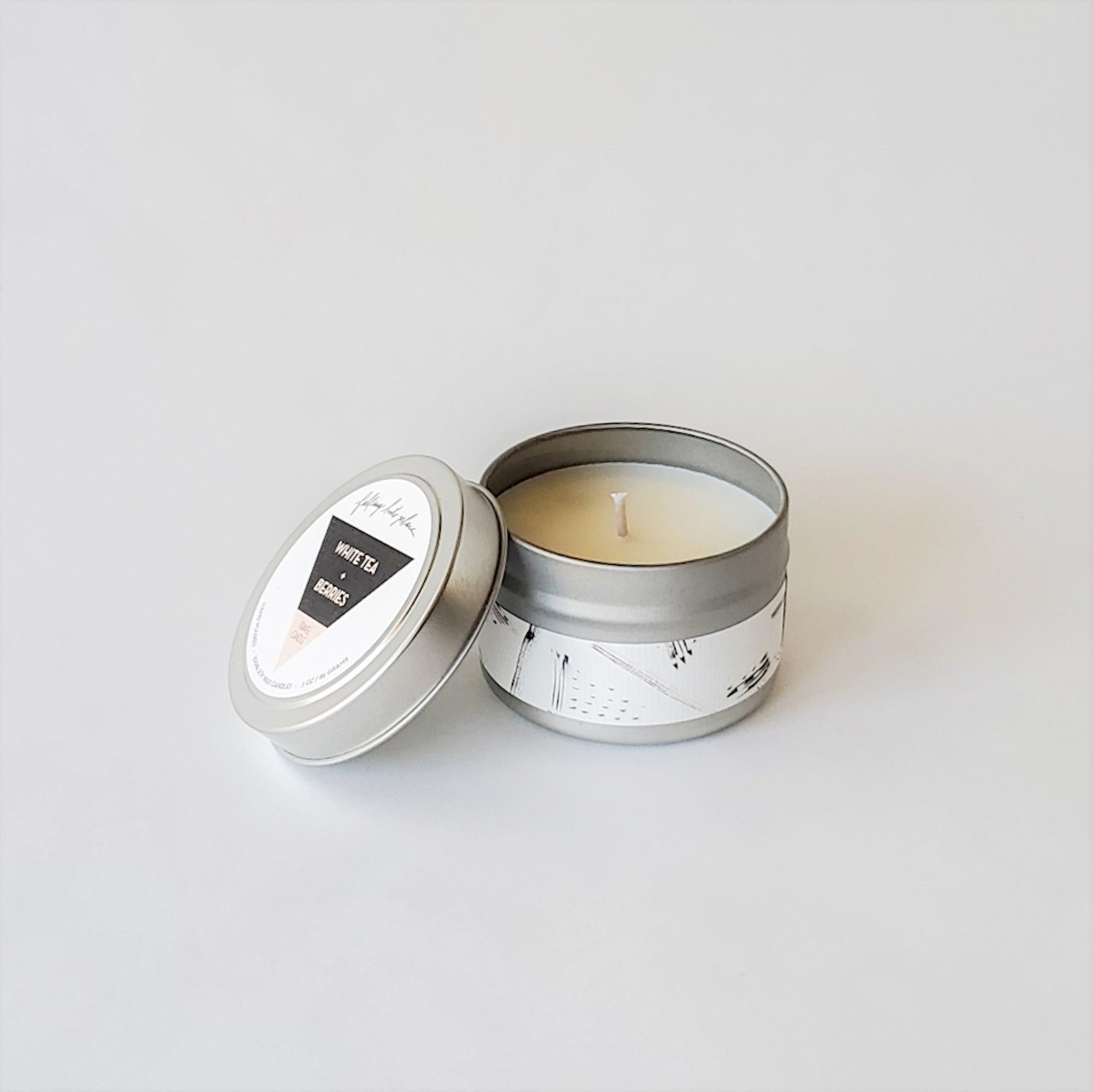 Artistic jar and tin candles with black and white labels. 